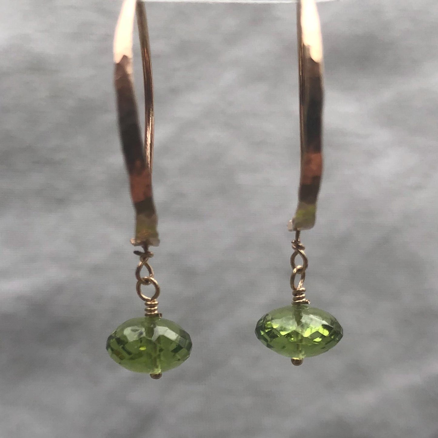Solid gold hoop earrings with faceted peridot drops