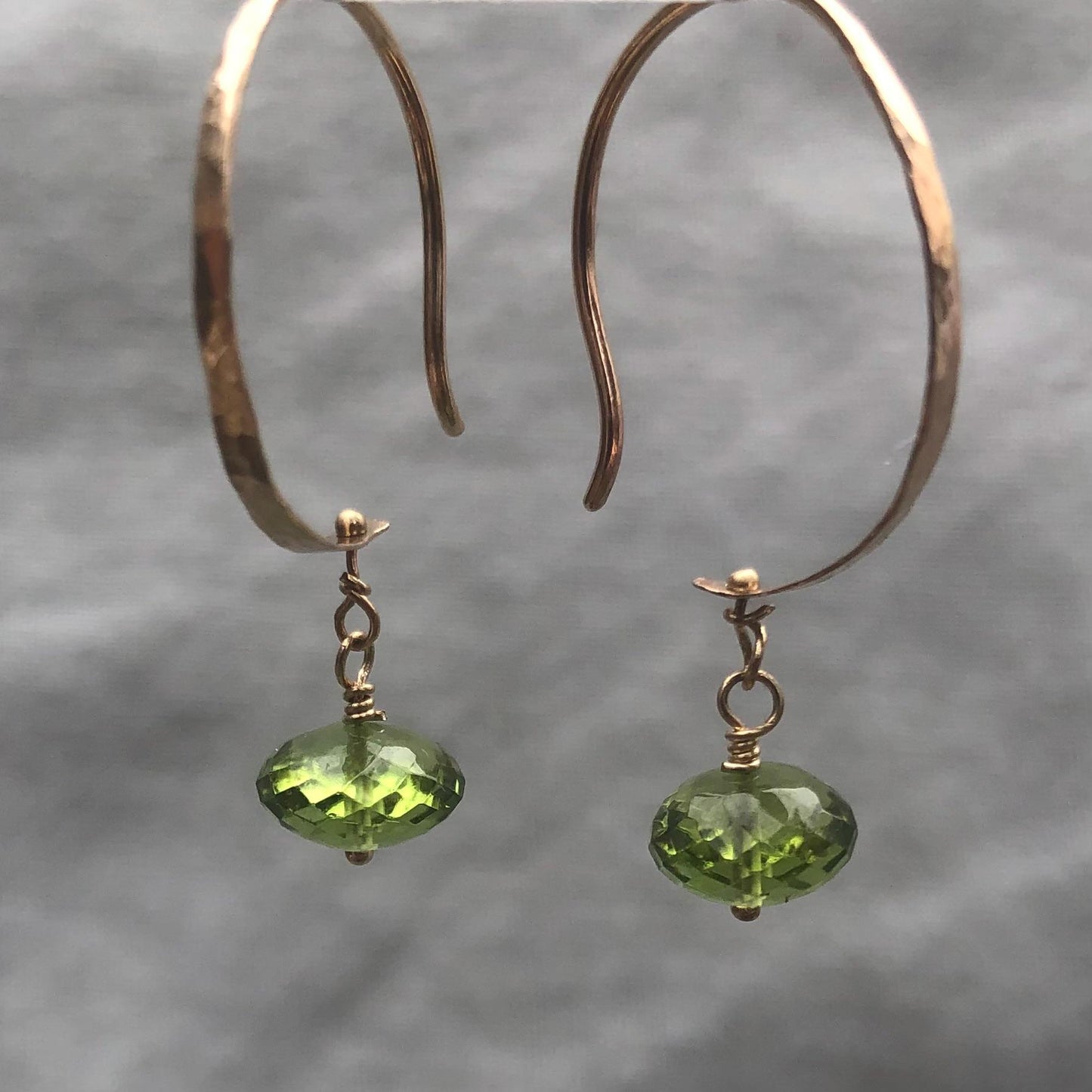 Solid gold hoop earrings with faceted peridot drops