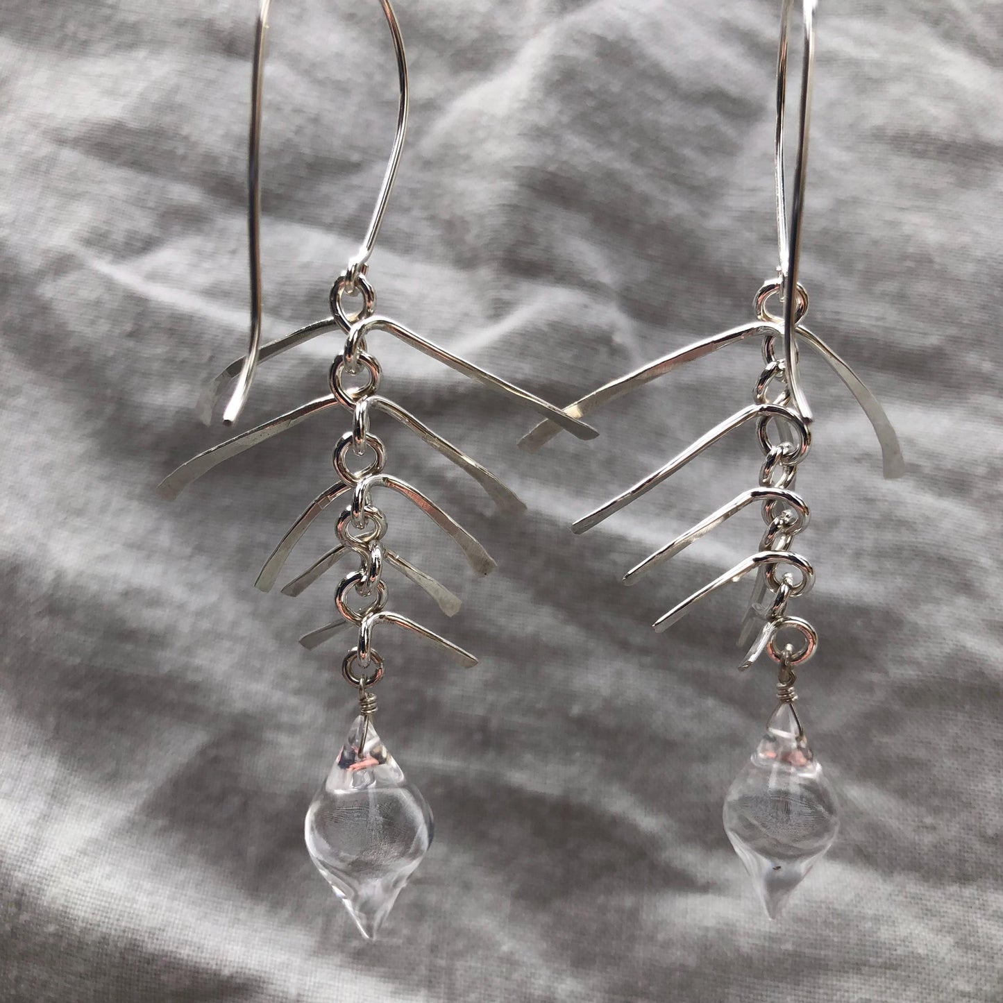 Kinetic sculptural earrings in hammered argentium sterling silver with clear quartz // Fishbone statement earrings with natural rock crystal