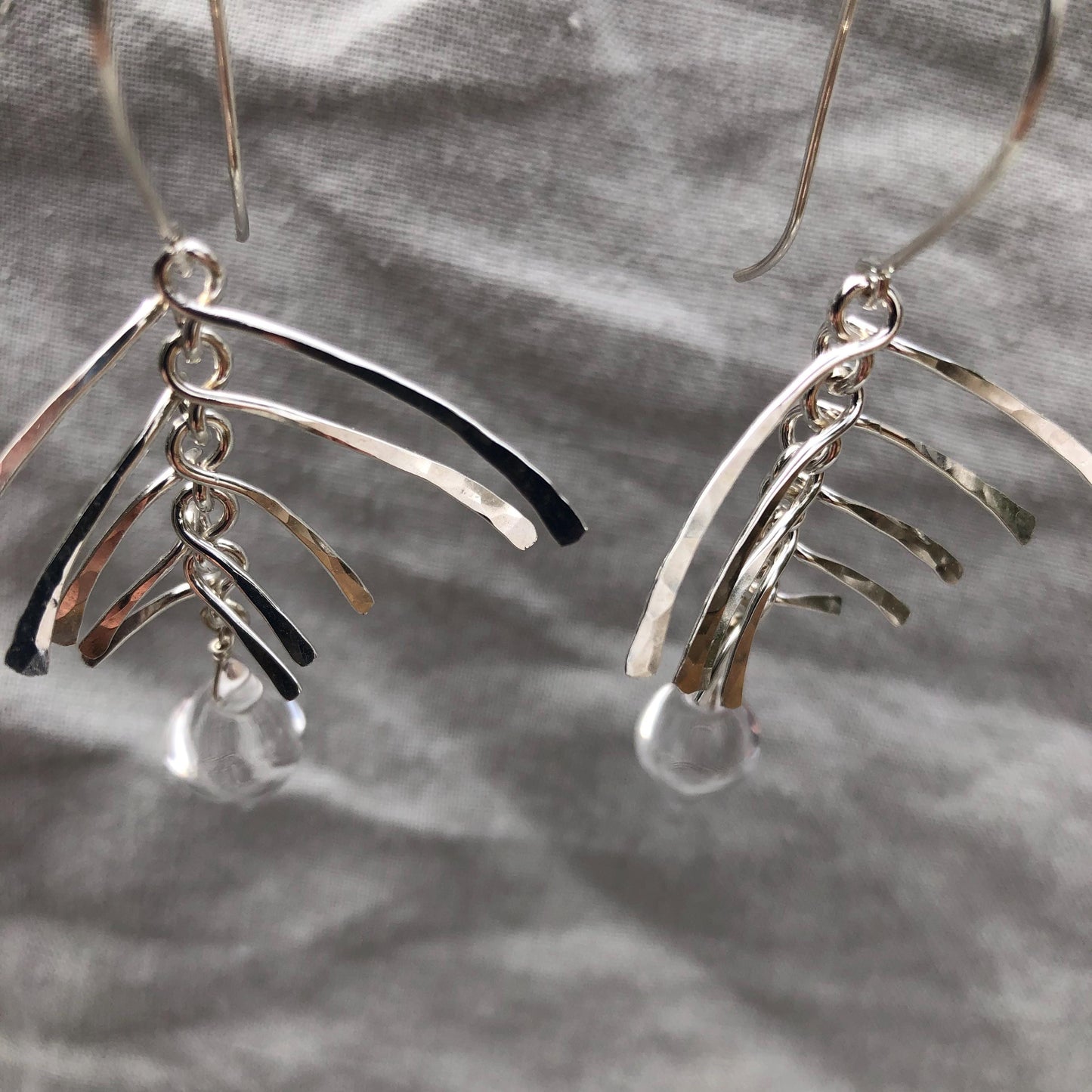 Kinetic sculptural earrings in hammered argentium sterling silver with clear quartz // Fishbone statement earrings with natural rock crystal