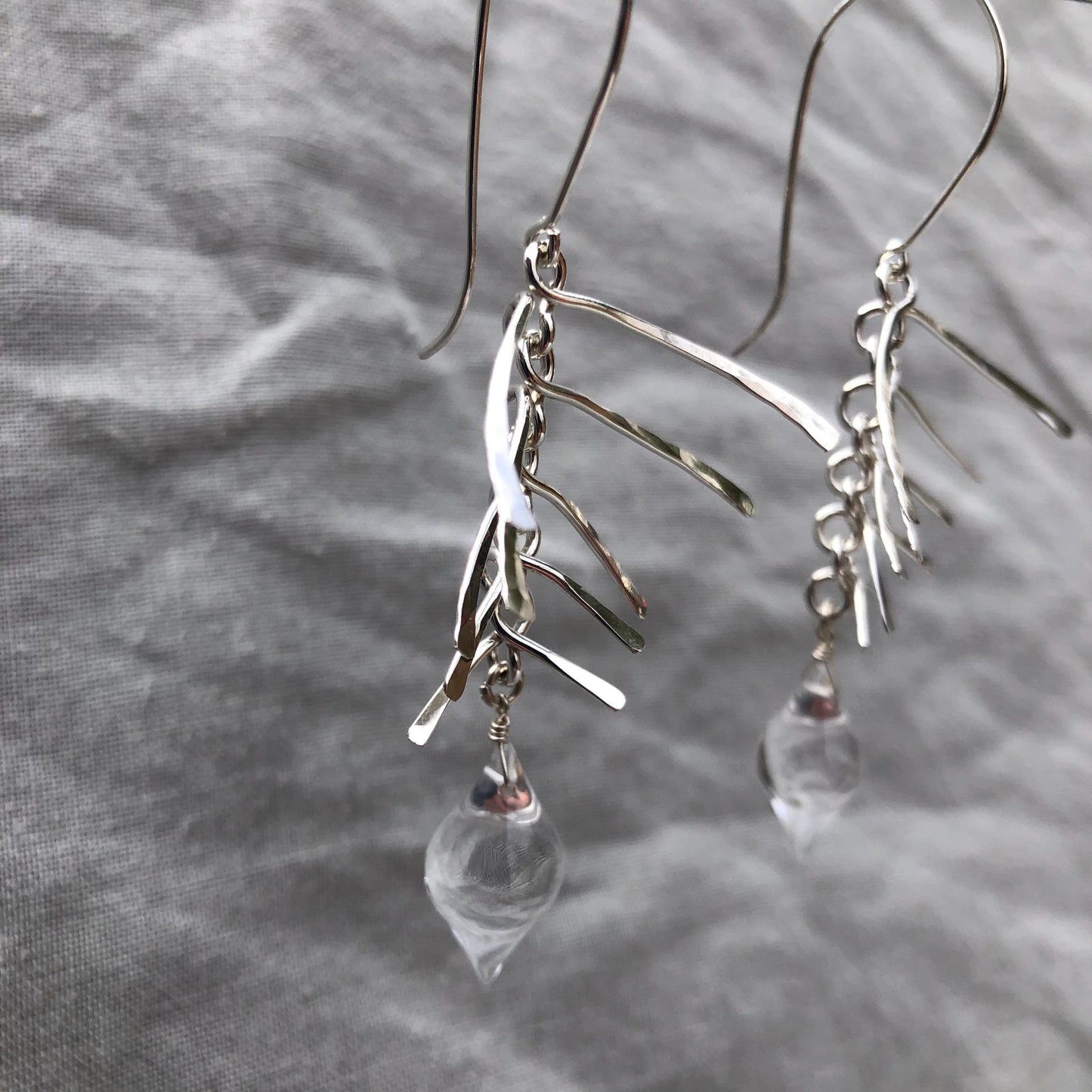 Kinetic sculptural earrings in hammered argentium sterling silver with clear quartz // Fishbone statement earrings with natural rock crystal