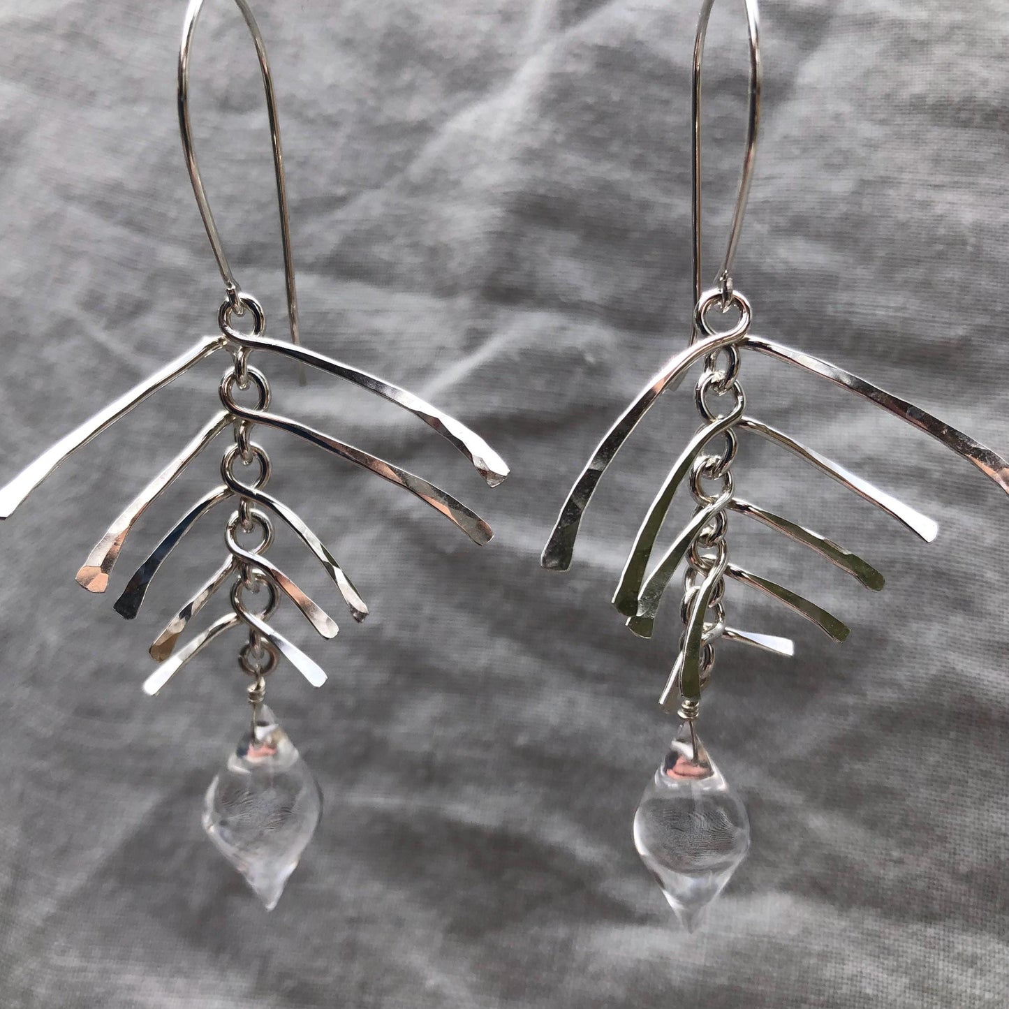Kinetic sculptural earrings in hammered argentium sterling silver with clear quartz // Fishbone statement earrings with natural rock crystal
