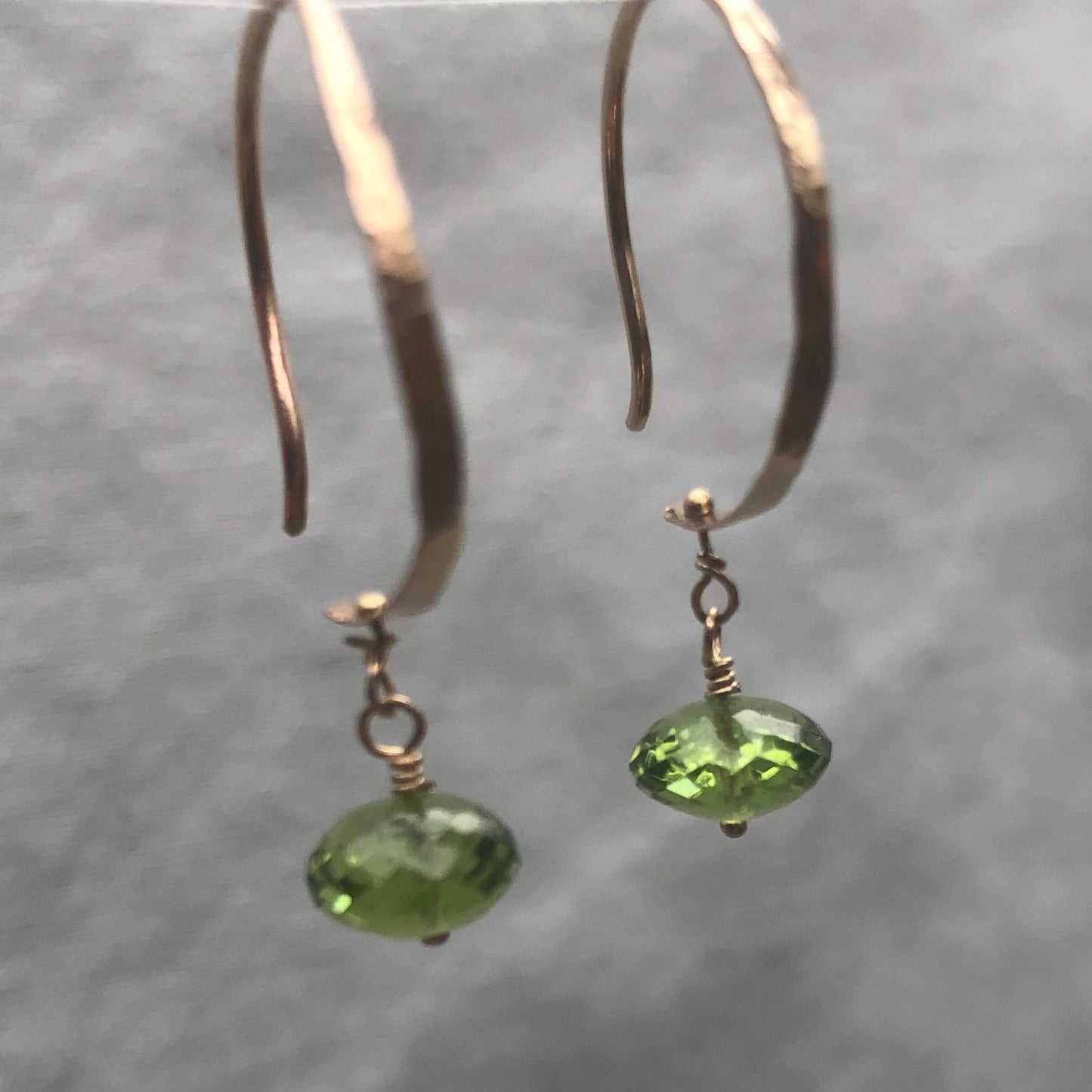 Solid gold hoop earrings with faceted peridot drops