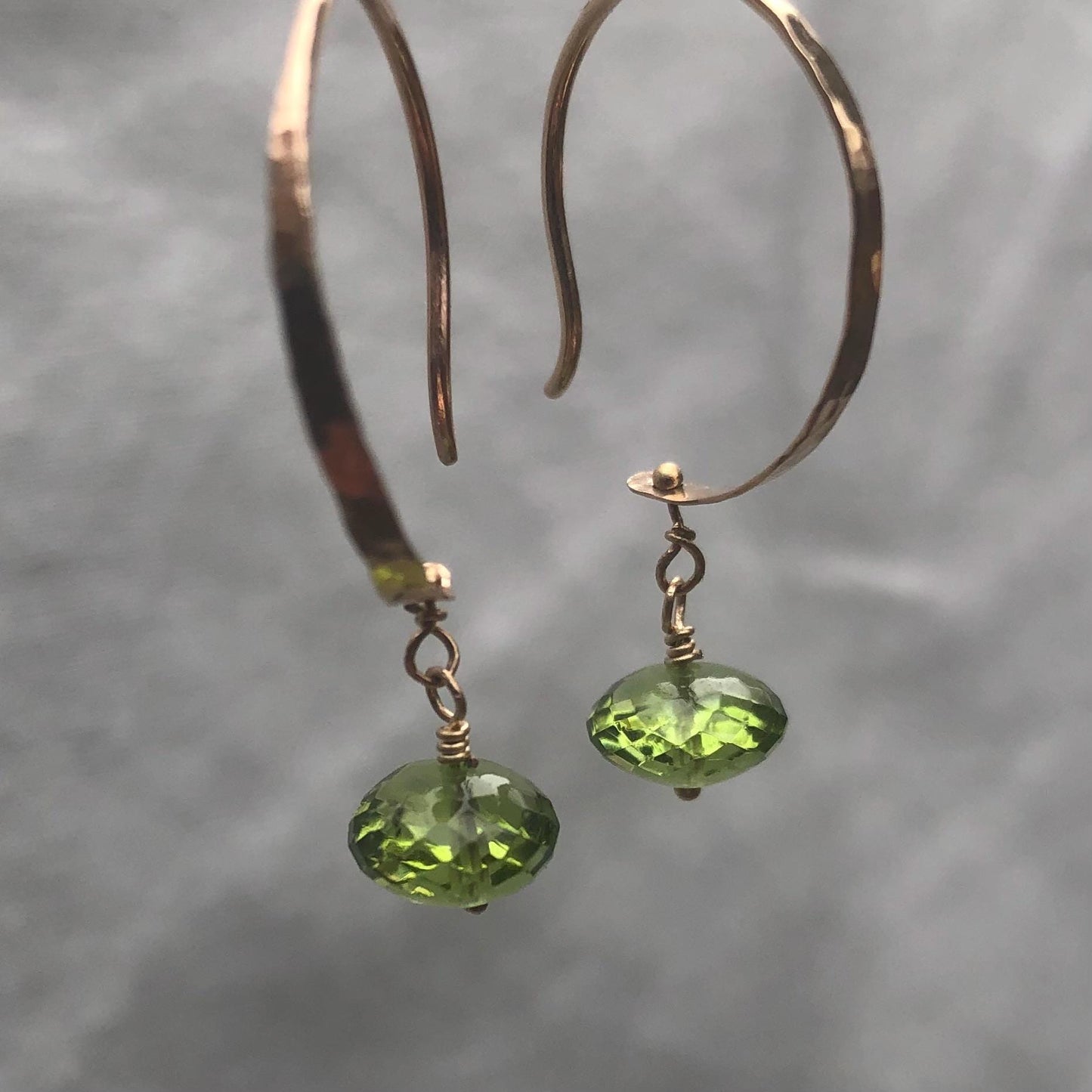Solid gold hoop earrings with faceted peridot drops