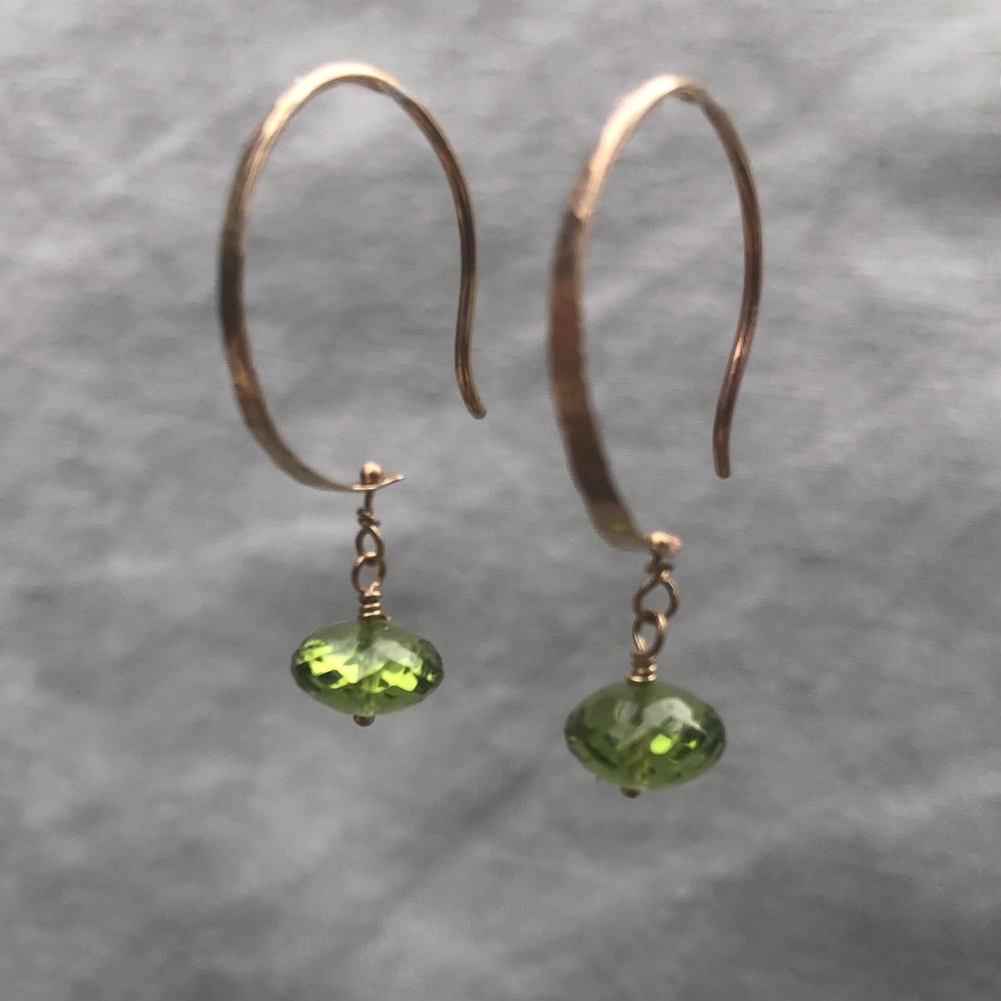 Solid gold hoop earrings with faceted peridot drops