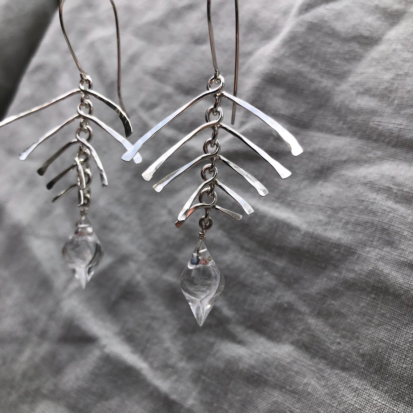 Kinetic sculptural earrings in hammered argentium sterling silver with clear quartz // Fishbone statement earrings with natural rock crystal