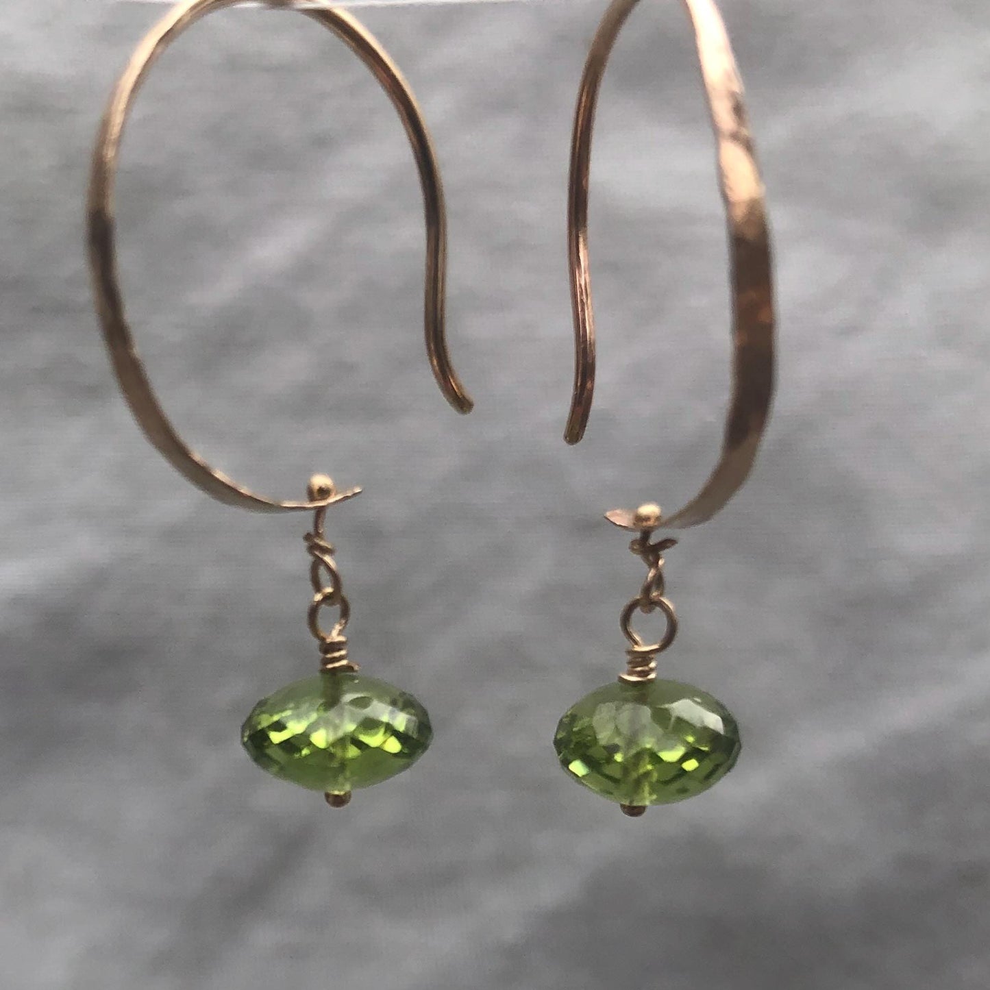 Solid gold hoop earrings with faceted peridot drops