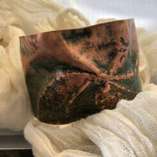 Pinwheel cuff bracelet in chased and repoussé copper with blue and green patina