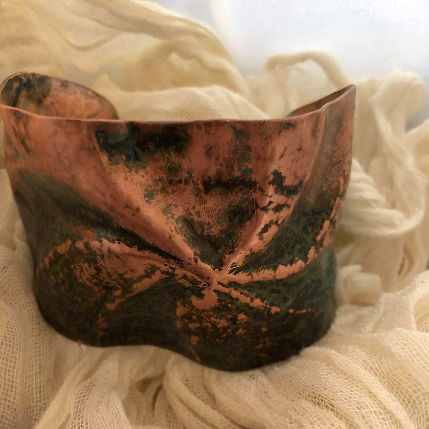 Pinwheel cuff bracelet in chased and repoussé copper with blue and green patina