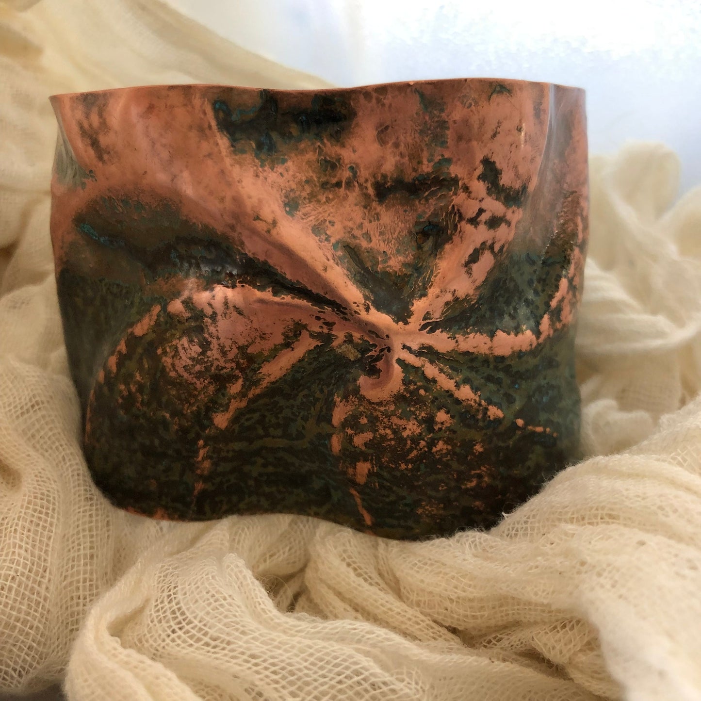 Pinwheel cuff bracelet in chased and repoussé copper with blue and green patina