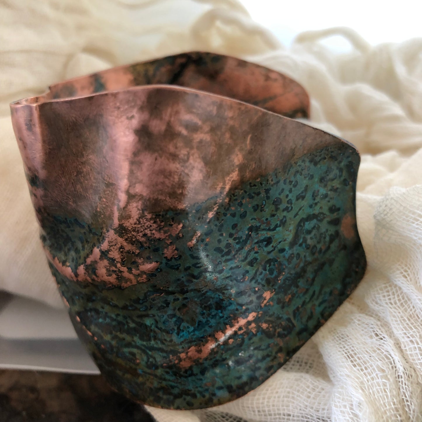 Pinwheel cuff bracelet in chased and repoussé copper with blue and green patina