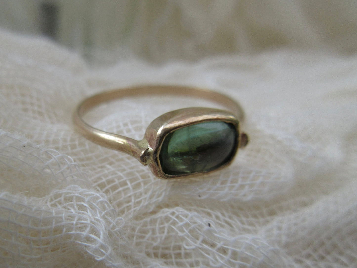 Candy ring in 14 karat gold with a light green tourmaline cabochon