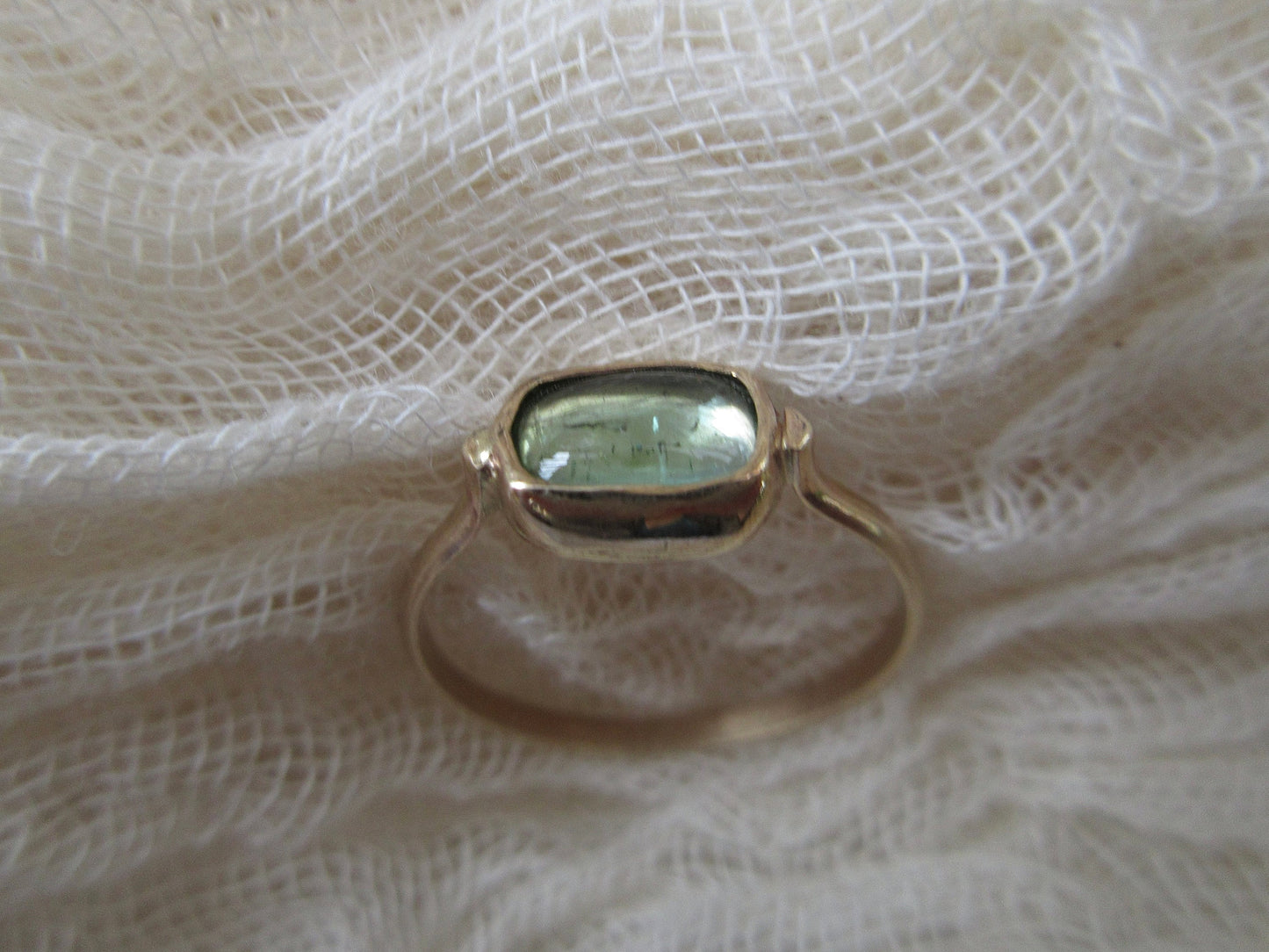 Candy ring in 14 karat gold with a light green tourmaline cabochon